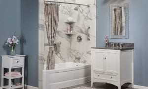 BA newly remodeled bathroom with a white bathtub, marble walls, and white furniture