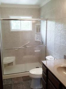 A newly remodeled bathroom shower with a shower seat and shevling