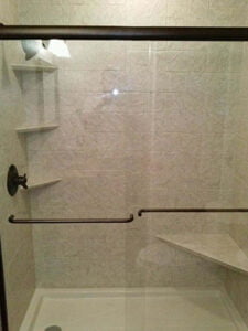 A newly remodeled shower with a seat, grab bars, and attractive shelving